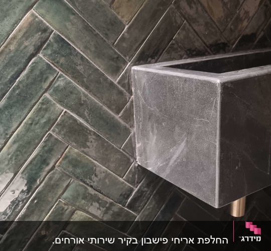 כיור אבן וברז זהב על רקע אריחים ירוקים